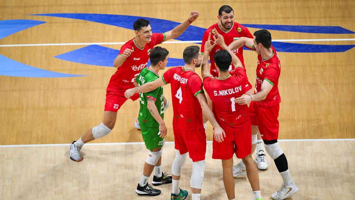 Grupa siatkarzy w czerwonych strojach świętuje razem z jednym graczem w zielonej koszulce na boisku sportowym.