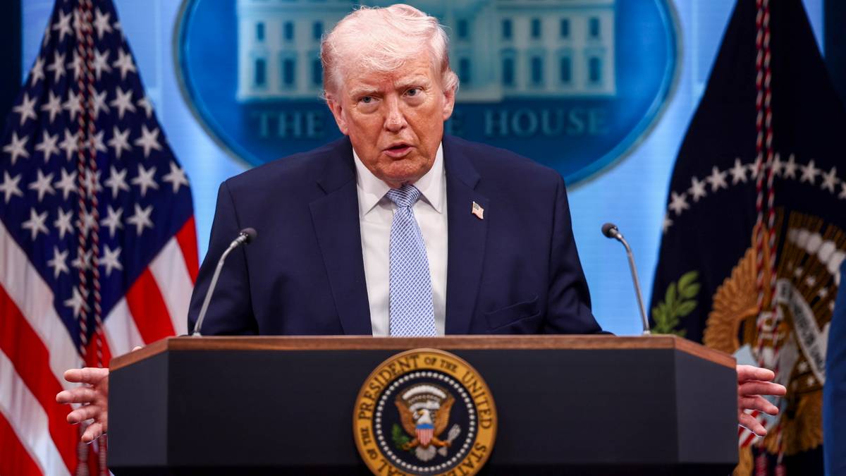 Donald Trump przemawia za m&oacute;wnicą z herbem USA, na tle flag USA i logo "The White House".