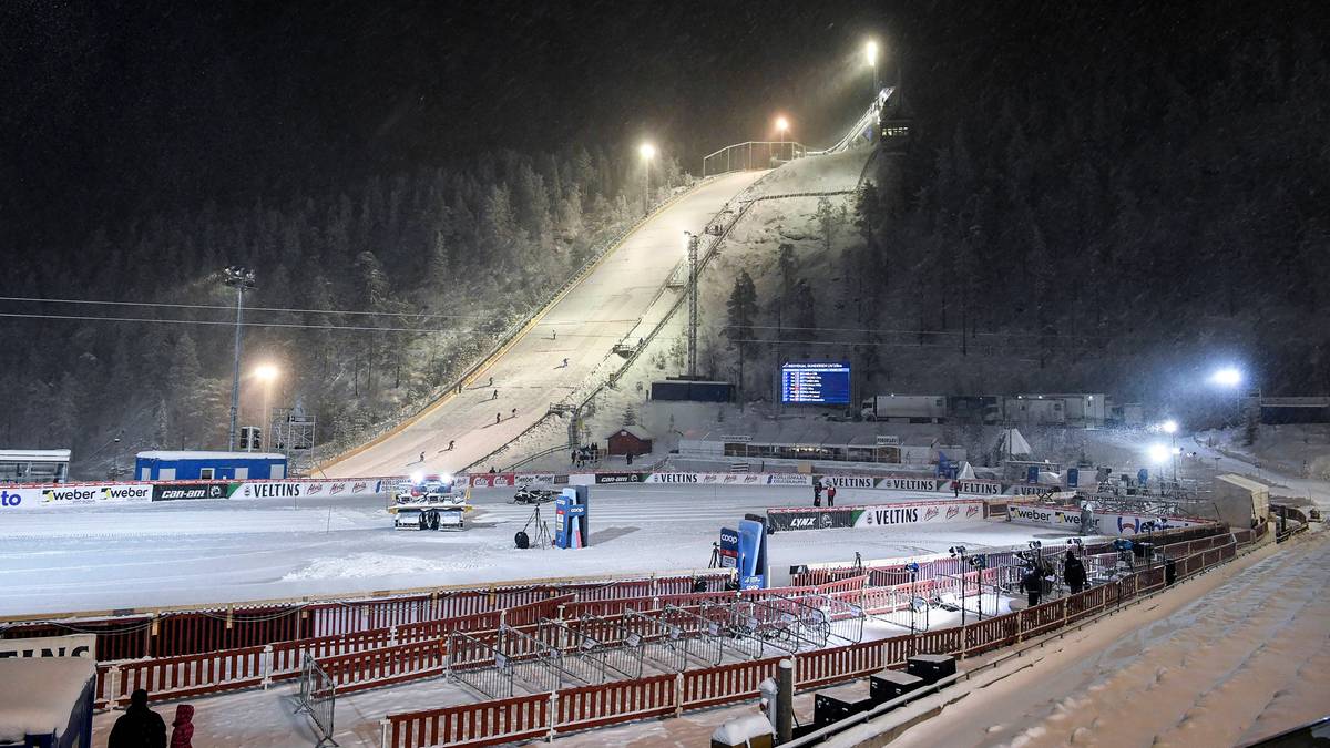 Oświetlona skocznia narciarska nocą, pokryta śniegiem.