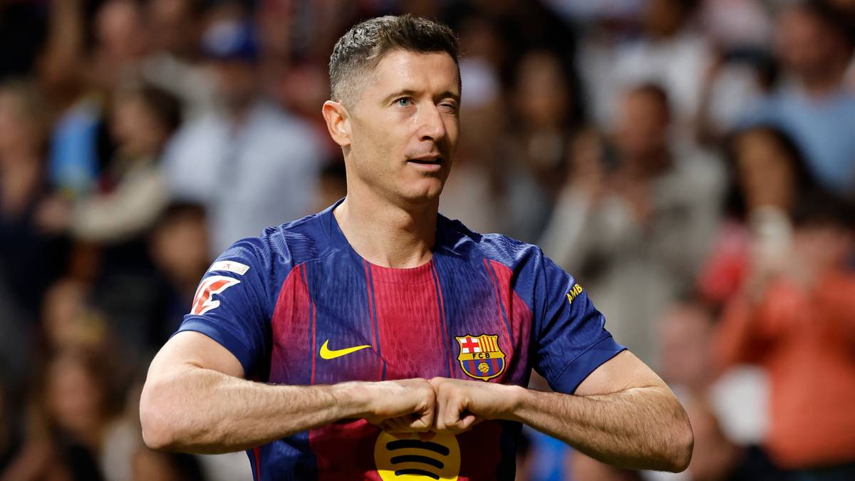Robert Lewandowski w koszulce FC Barcelony, z rękami splecionymi przed sobą, na tle trybun stadionu.