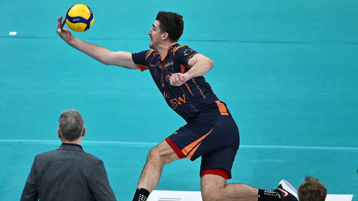 Siatkarz w skoku do ataku z piłką w dłoni.