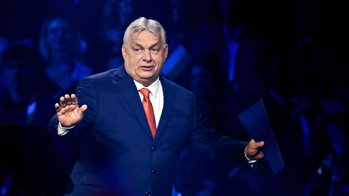 Viktor Orban przemawia na scenie w ciemnym garniturze i czerwonym krawacie.