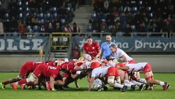 Zawodnicy rugby w młynie podczas meczu, na zielonej murawie stadionu.