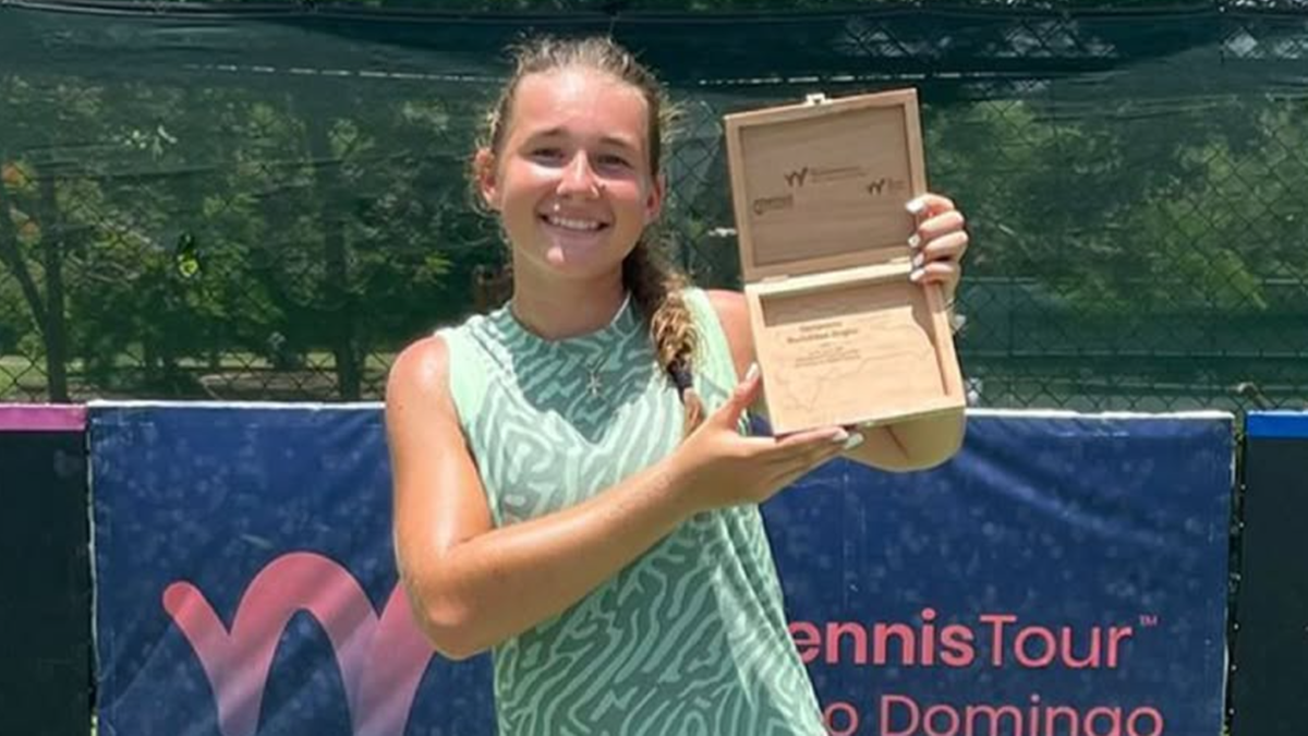 Uśmiechnięta młoda tenisistka trzymająca drewniane pudełko na trofeum.