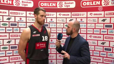Koszykarz w czarnej koszulce z numerem 18 udziela wywiadu dziennikarzowi.
