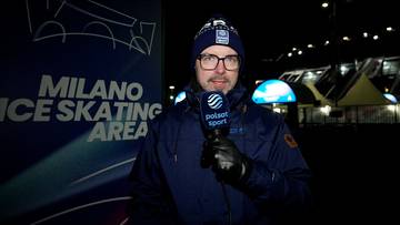Marcin Lepa, dziennikarz Polsatu Sport, w zimowej czapce i okularach, trzyma mikrofon i stoi przed planszą "MILANO ICE SKATING AREA" w nocy.