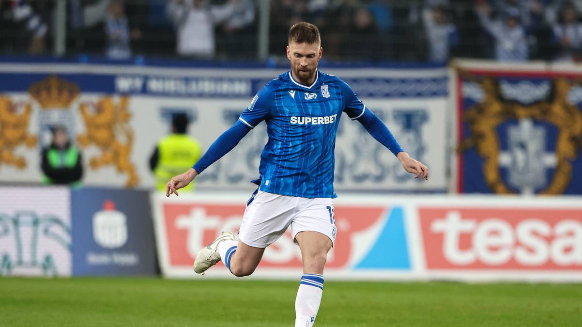 Piłkarz w niebieskim stroju Lecha Poznań biegnie po boisku.