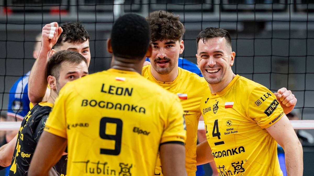 Siatkarze w ż&oacute;łtych koszulkach z numerami i napisami, uśmiechający się i rozmawiający.