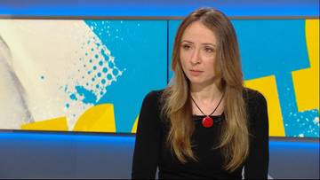 Kobieta siedząca w studiu telewizyjnym przed ekranem z kolorowym tłem.