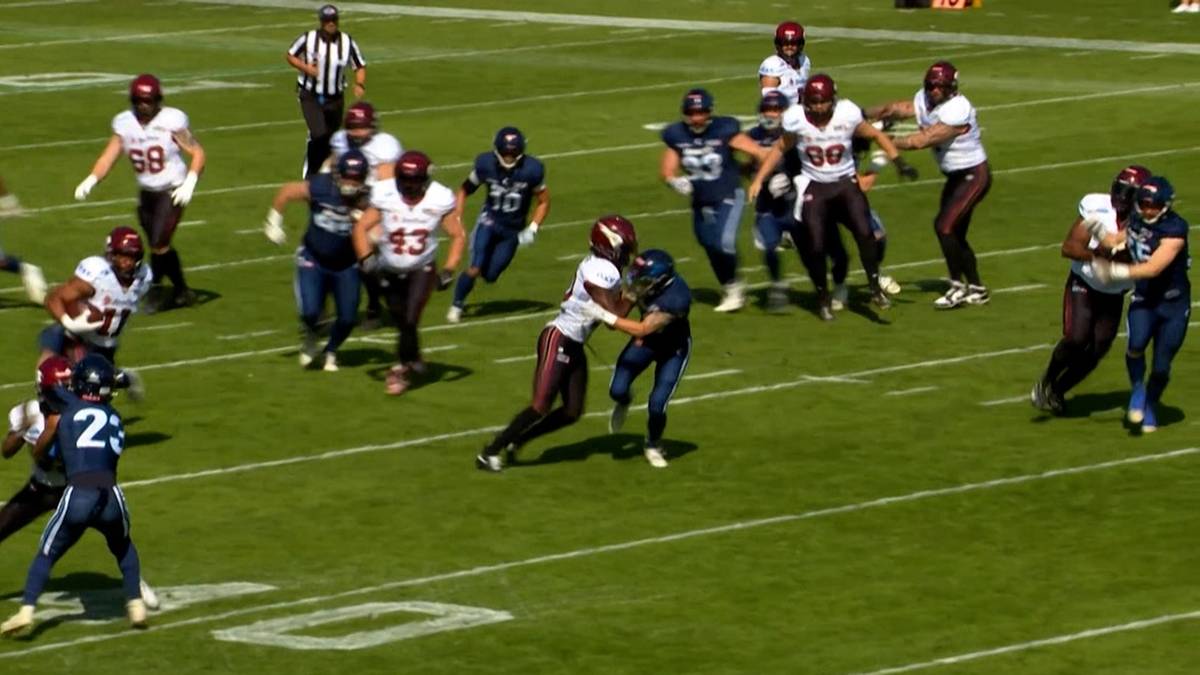 Gracze futbolu amerykańskiego w akcji na zielonym boisku podczas meczu.