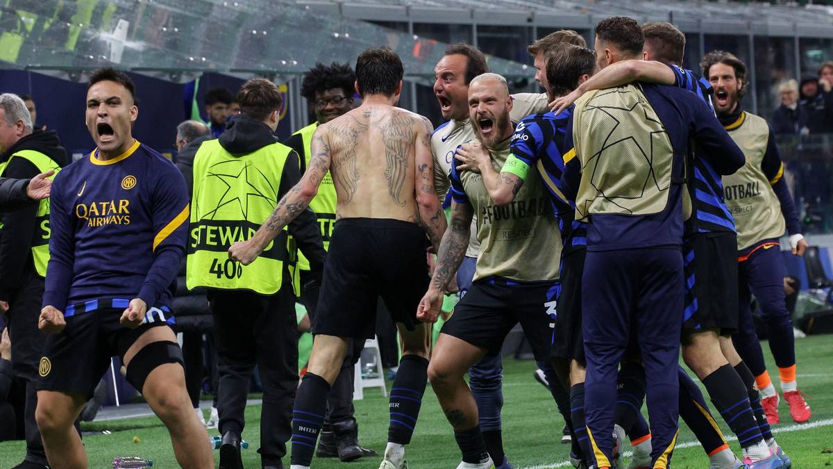 Grupa piłkarzy świętuje zwycięstwo na boisku, niektórzy przytulają się i unoszą ręce w geście radości.