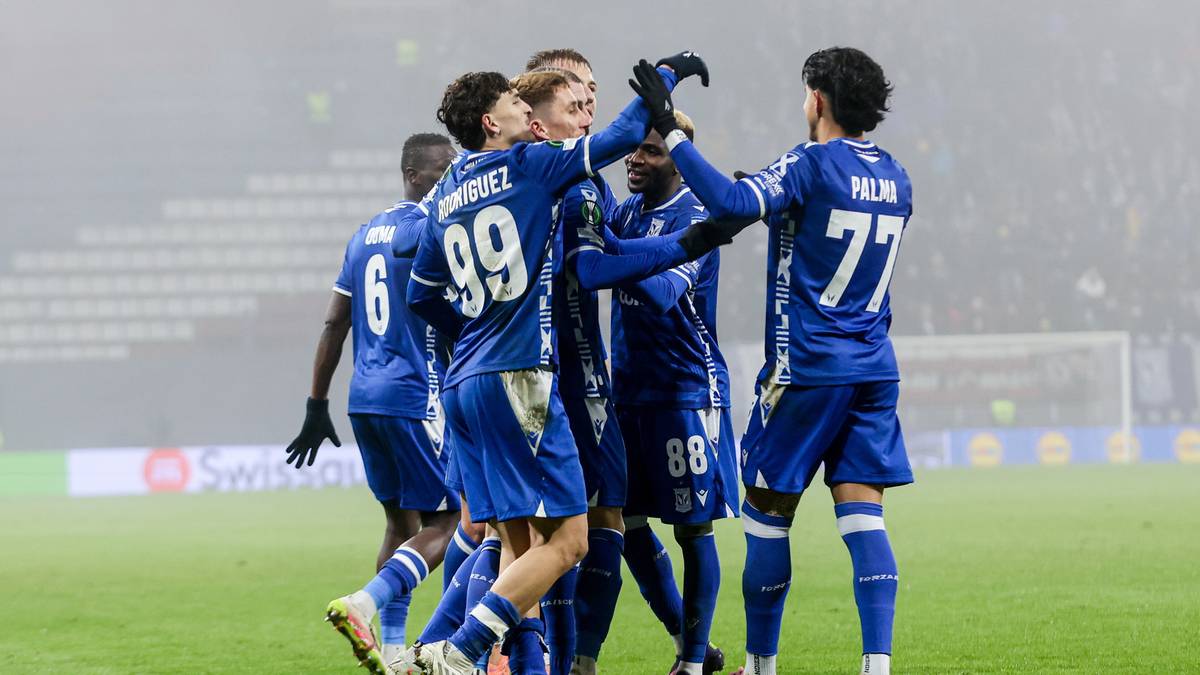 Piłkarze w niebieskich strojach świętują bramkę na boisku.