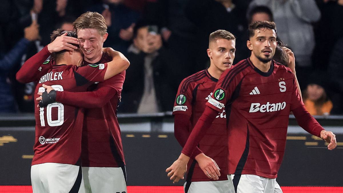 Piłkarze w czerwonych strojach świętują gola, jeden obejmuje drugiego, pozostali patrzą z radością.