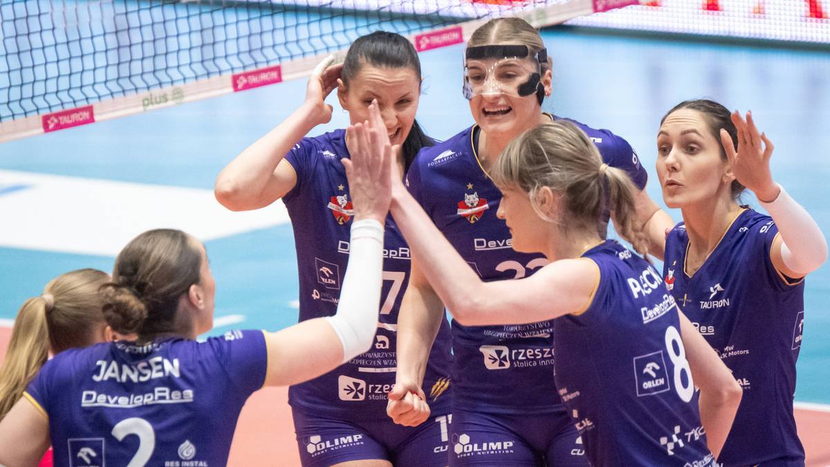Siatkarki Developres Rzesz&oacute;w w niebieskich strojach sportowych świętują zwycięstwo na boisku siatkarskim, podając sobie "piątki".