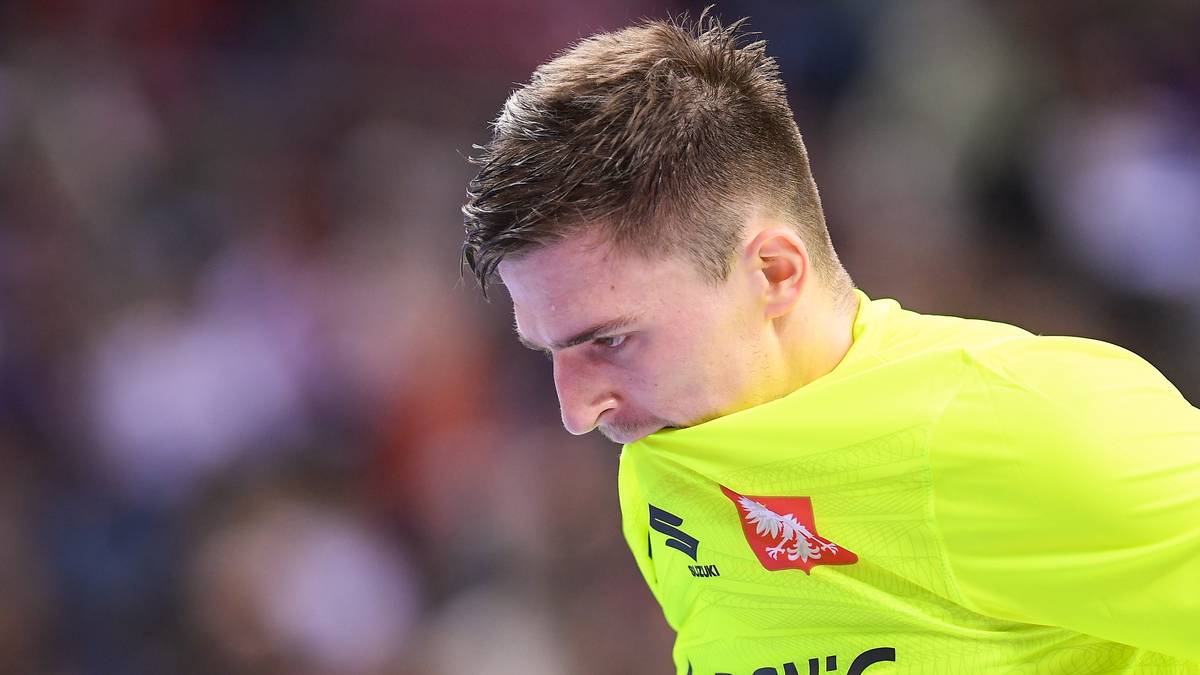 Portret zawodnika piłki ręcznej w ż&oacute;łtej koszulce, z bliska, patrzącego w d&oacute;ł.