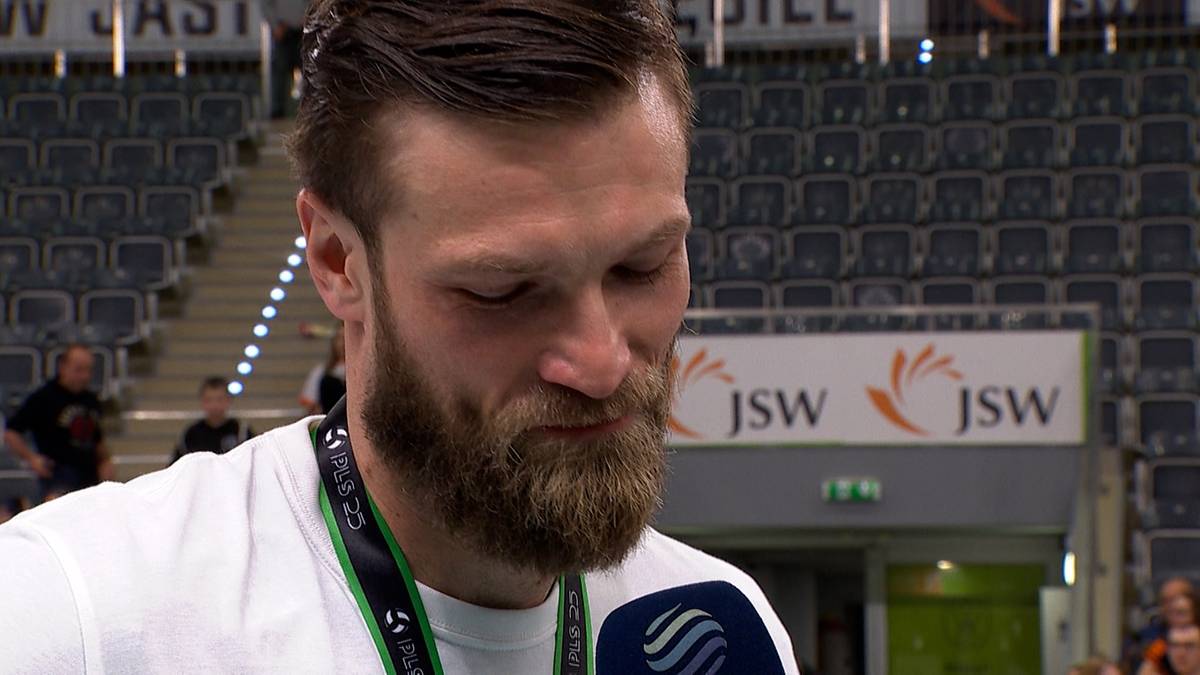 Portret Andrzeja Wrony, siatkarza, z brodą i łzami w oczach, na tle trybun sportowych.