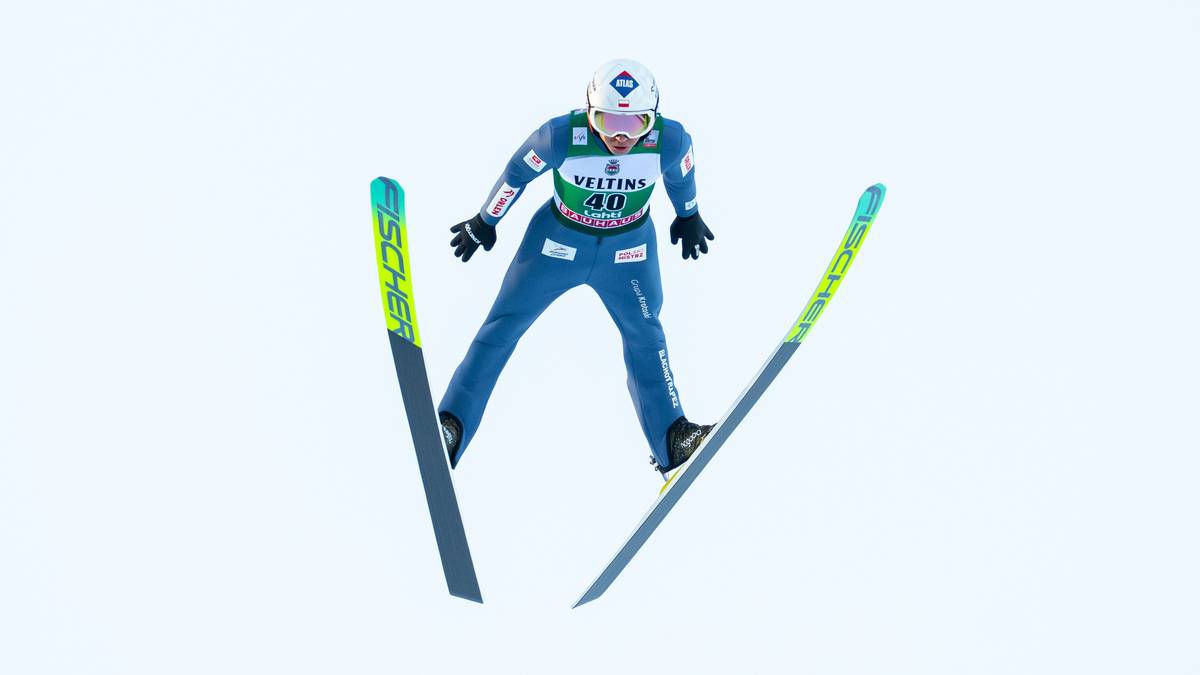 Skoczek narciarski w powietrzu podczas skoku na nartach.