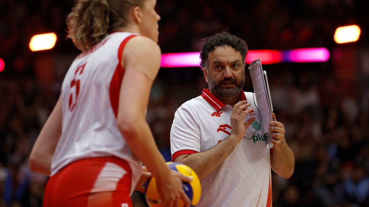 Trener siatkówki z tablicą obserwuje zawodniczkę.