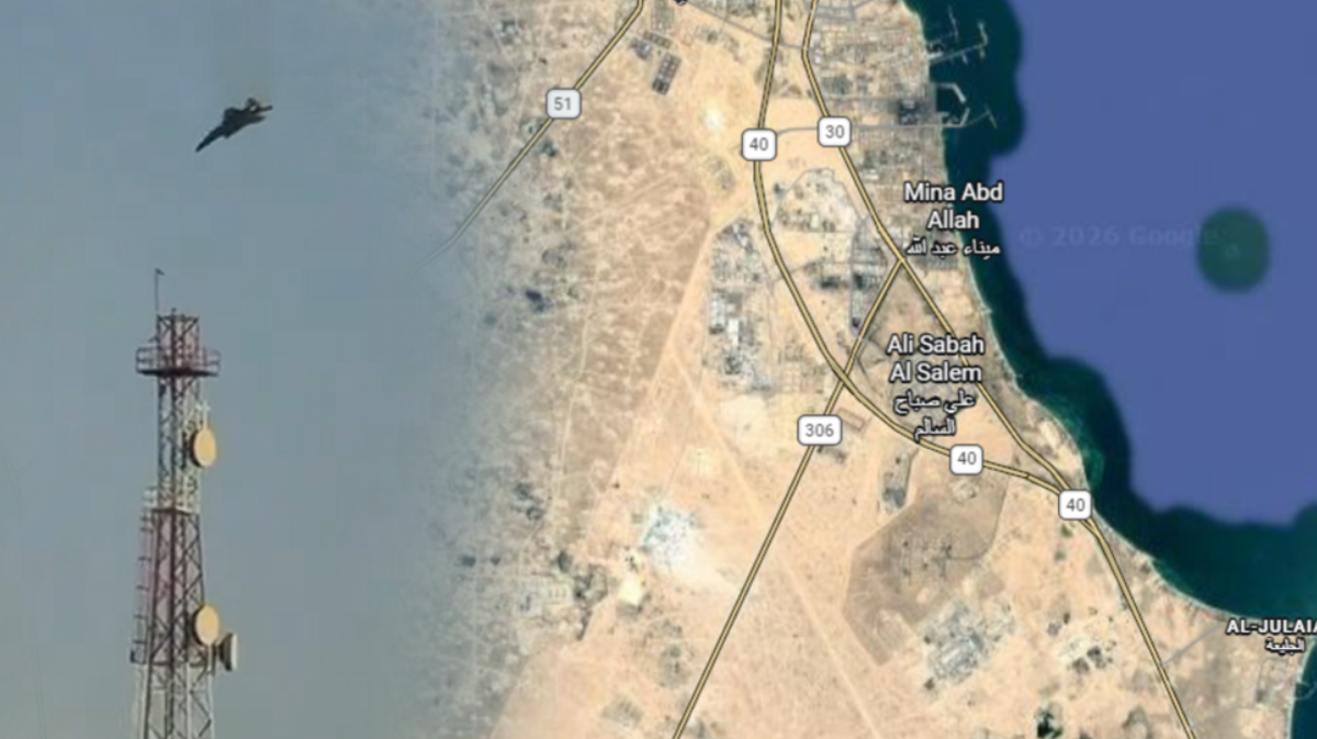 Widok z lotu ptaka na pustynny krajobraz z fragmentem wybrzeża. Na pierwszym planie po lewej stronie znajduje się wysoka wieża telekomunikacyjna z antenami. Powyżej niej, na tle jasnego nieba, leci amerykański samolot wojskowy.