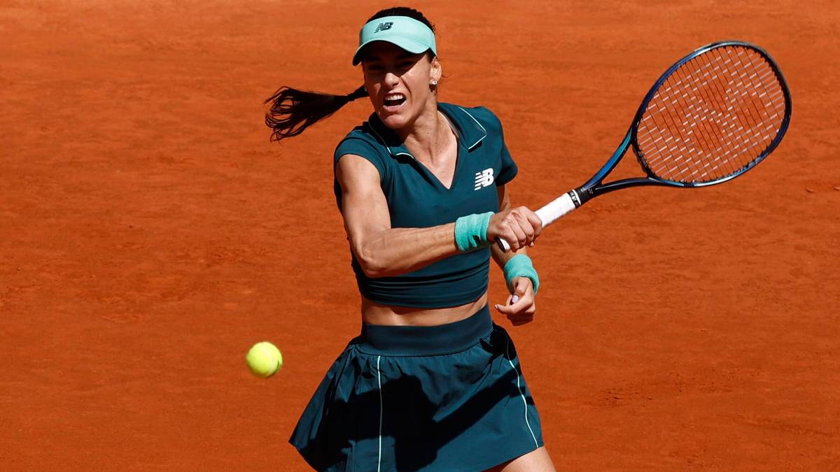 Tenisistka Sorana Cirstea podczas meczu na korcie ziemnym, wykonująca uderzenie.