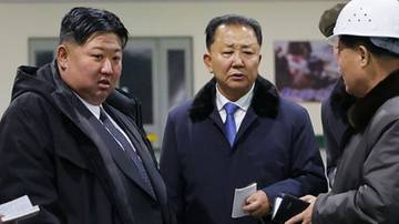 Kim Dzong Un w towarzystwie innych os&oacute;b wewnątrz hali produkcyjnej.