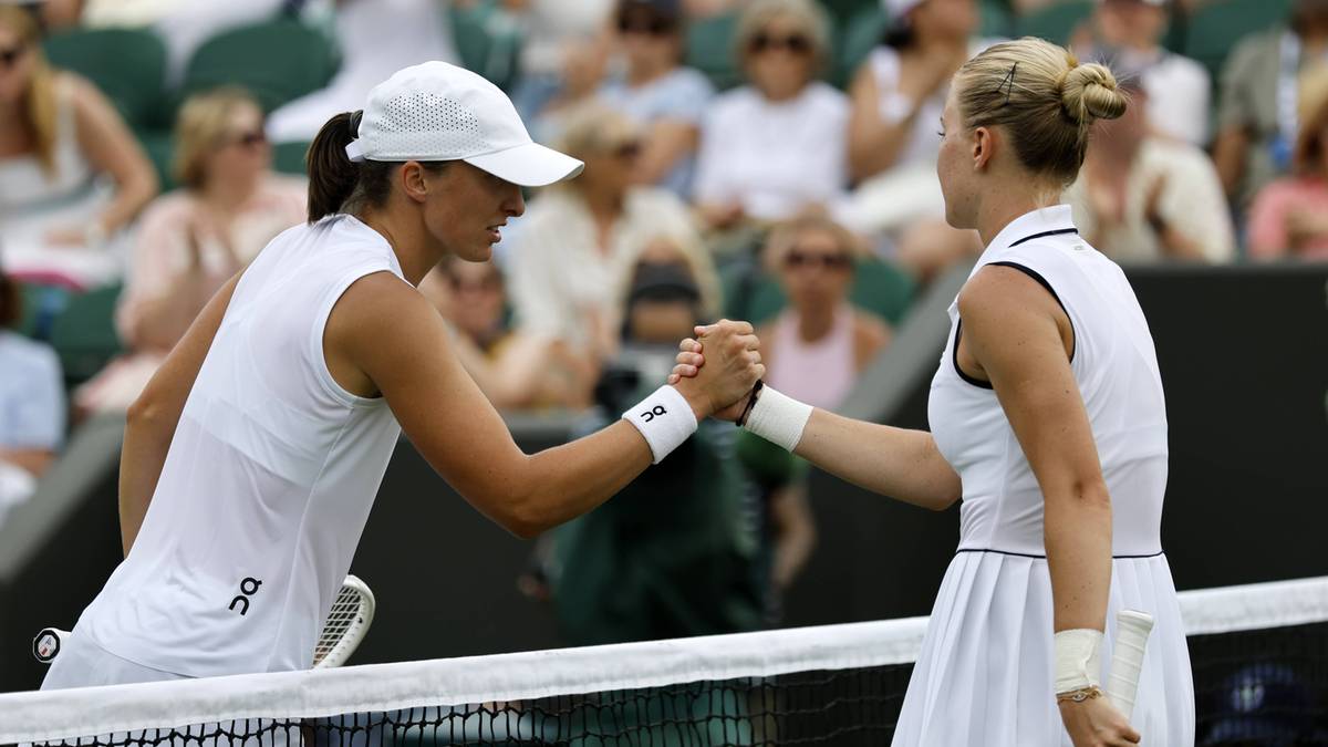 Dwie kobiety w strojach tenisowych ściskają sobie dłonie nad siatką na korcie tenisowym.