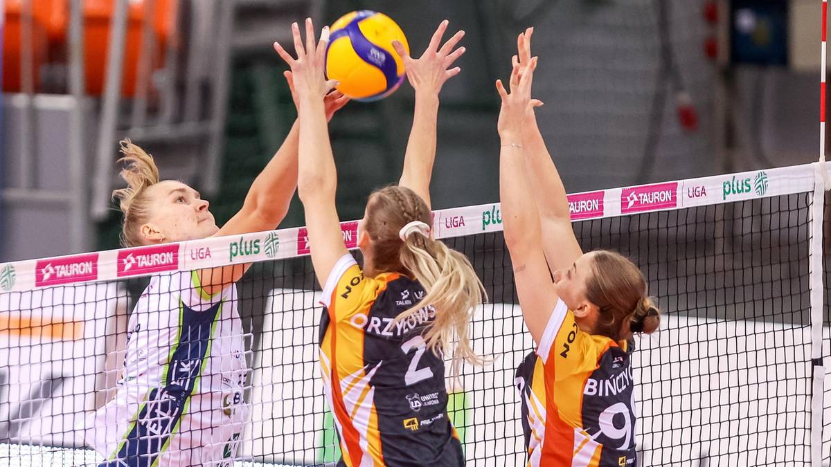 Siatkarki w akcji podczas meczu Tauron Puchar Polski, pr&oacute;bujące zablokować atak przeciwniczki.