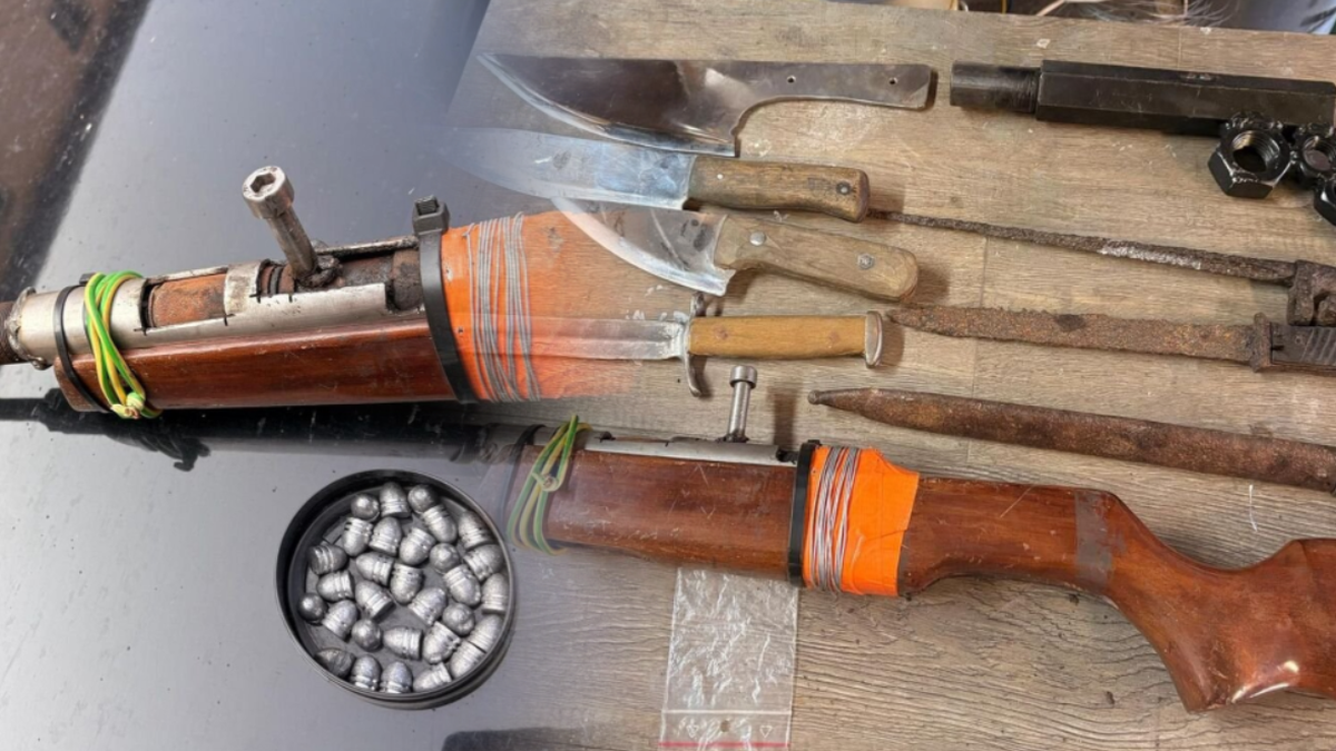 Na zdjęciu widoczne są części broni palnej, noże oraz pociski, a także elementy sugerujące materiały wybuchowe.