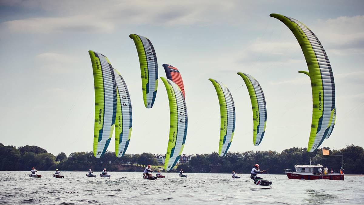 Grupa kitesurfer&oacute;w z latawcami na wodzie podczas zawod&oacute;w.