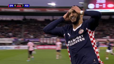 Piłkarz PSV Eindhoven świętuje bramkę, trzymając ręce na głowie. W tle widać innych zawodnik&oacute;w i trybuny stadionu.