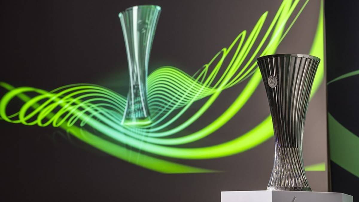 Dwa puchary Ligi Konferencji UEFA na tle zielono-żółtego motywu graficznego.