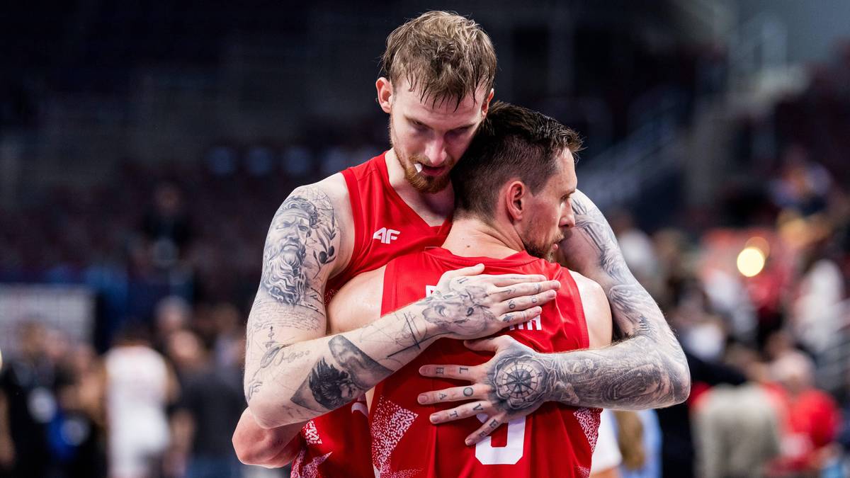 Dwóch koszykarzy w czerwonych strojach obejmuje się, jeden z nich ma ręce na plecach drugiego. Obaj mają tatuaże na ramionach.