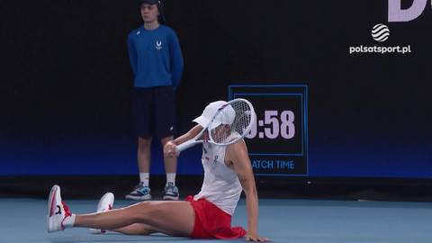 Iga Świątek leży na korcie tenisowym, trzymając rakietę po upadku.