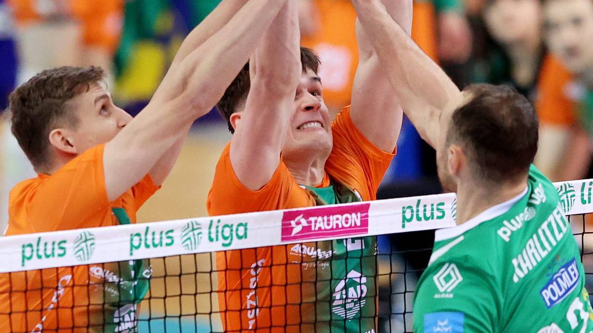 Siatkarze świętujący punkt, unosząc ręce w geście radości.