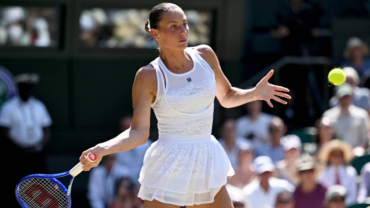 Tenisistka w białym stroju odbija piłkę rakietą podczas meczu na Wimbledonie.