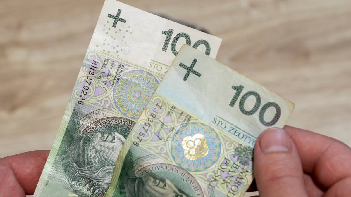 Dłonie trzymające dwie stuzłotowe banknoty.