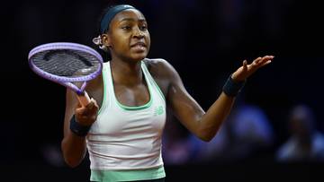 Coco Gauff trzyma rakietę tenisową i podnosi rękę w geście protestu lub zdziwienia podczas meczu.