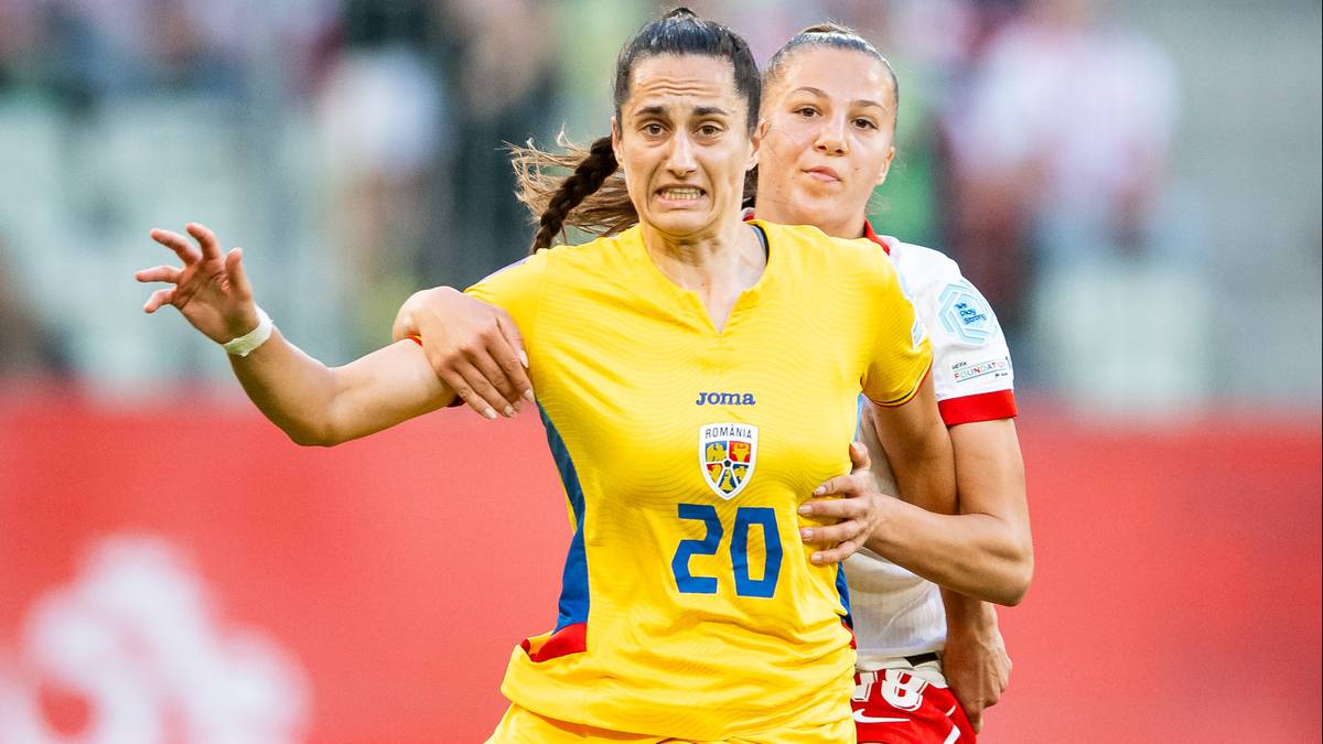Piłkarka w żółtej koszulce z numerem 20 i herbem Rumunii, zdeterminowana, biegnie po boisku. W tle widać inną zawodniczkę i trybuny.