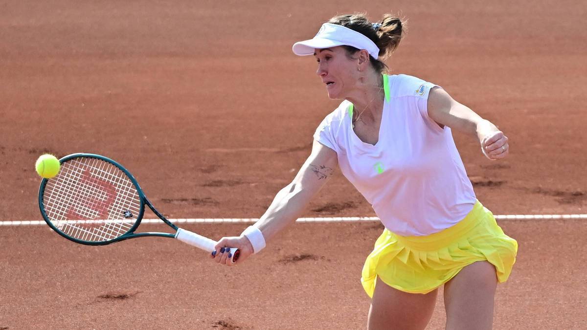 Tenisistka Katarzyna Kawa w akcji, uderza rakietą piłkę podczas meczu na korcie ziemnym.