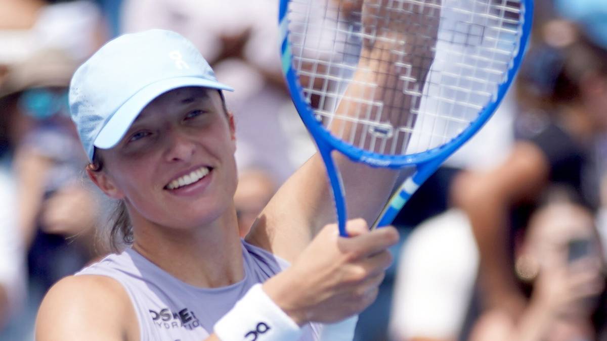 Uśmiechnięta tenisistka z jasną czapką i opaską na przedramieniu, trzymająca rakietę tenisową.