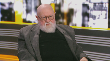 Portret Jerzego Bralczyka, starszego mężczyzny z siwą brodą i okularami.