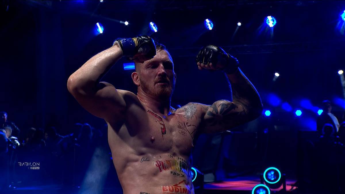 Marcin Łazarz unosi ręce w geście zwycięstwa na ringu.