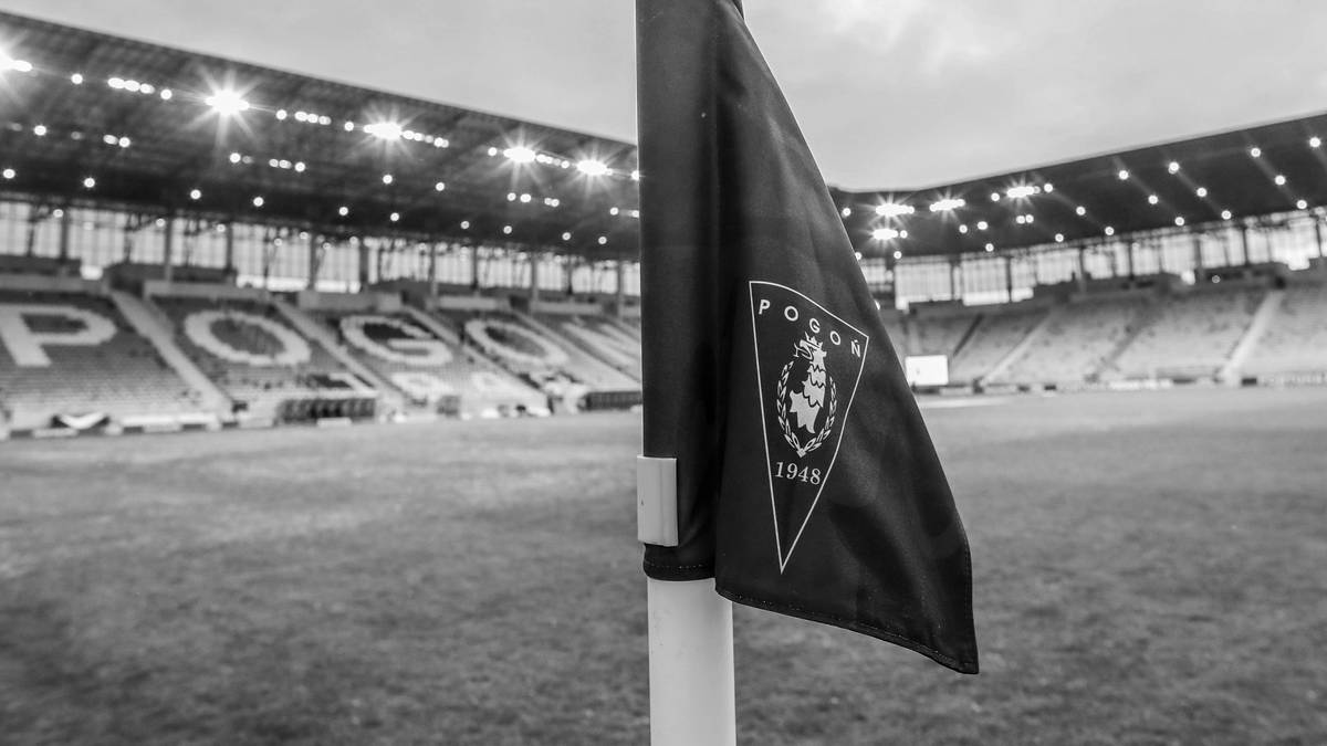 Flaga z herbem Pogoni Szczecin na tle stadionu.