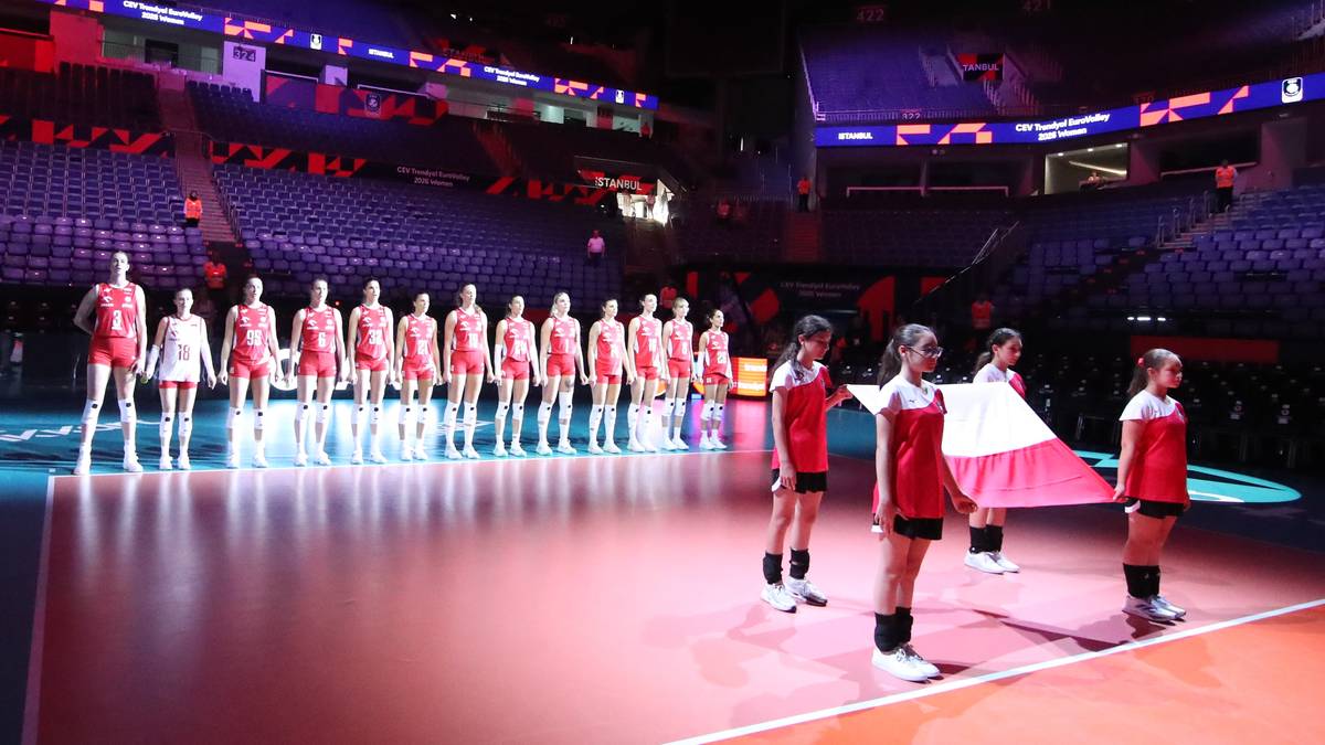 Zawodniczki reprezentacji w siatkówce stoją na parkiecie hali sportowej podczas ceremonii przed meczem.