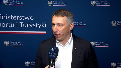 Sławomir Szmal, polski piłkarz ręczny, w czarnym garniturze, z białą koszulą, udziela wywiadu przed niebieską ścianką z logo Ministerstwa Sportu i Turystyki.