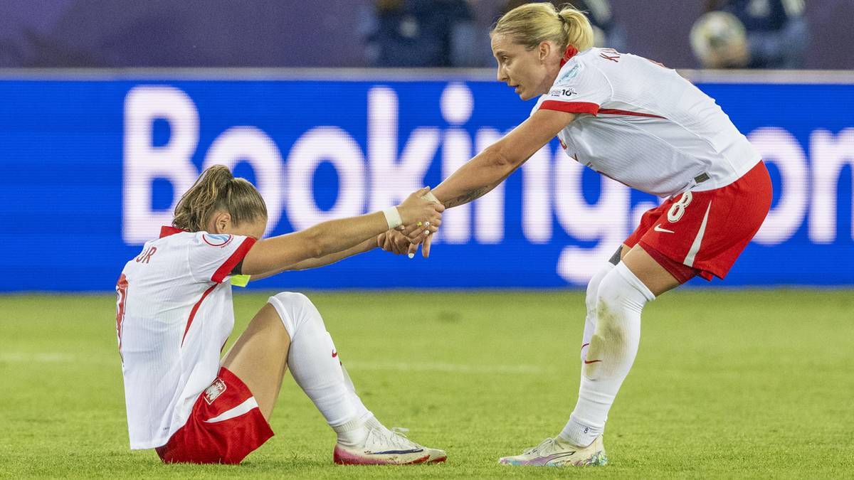 Piłkarka podaje rękę koleżance z drużyny siedzącej na boisku.