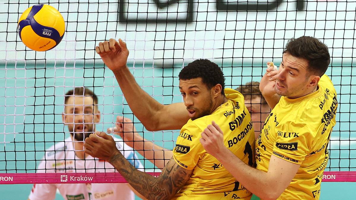 Siatkarze w ż&oacute;łtych strojach blokują atak przeciwnika.