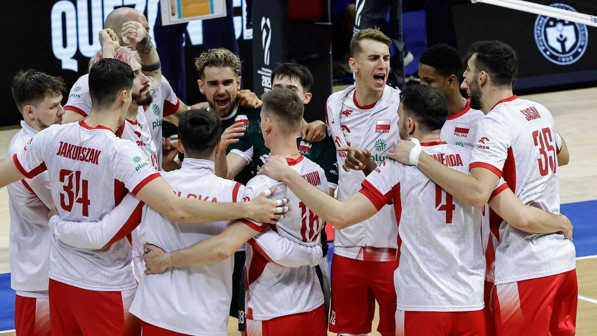 Drużyna siatkarzy w biało-czerwonych strojach świętuje w środku hali.