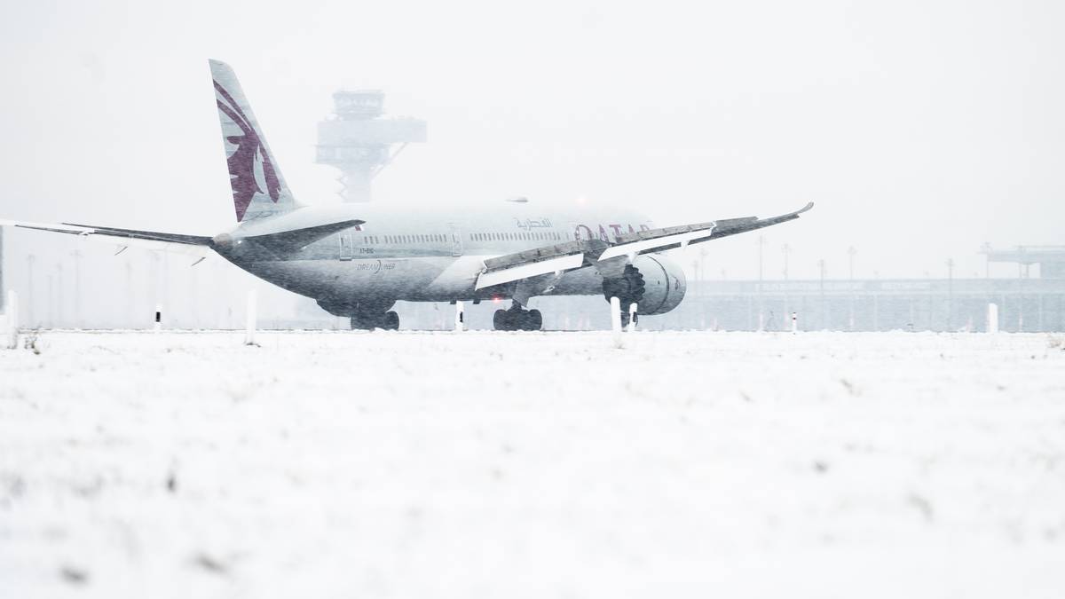Samolot linii Qatar Airways na zaśnieżonym pasie startowym.