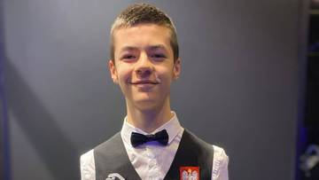 Portret młodego mężczyzny w stroju do snookera, z uśmiechem na twarzy.